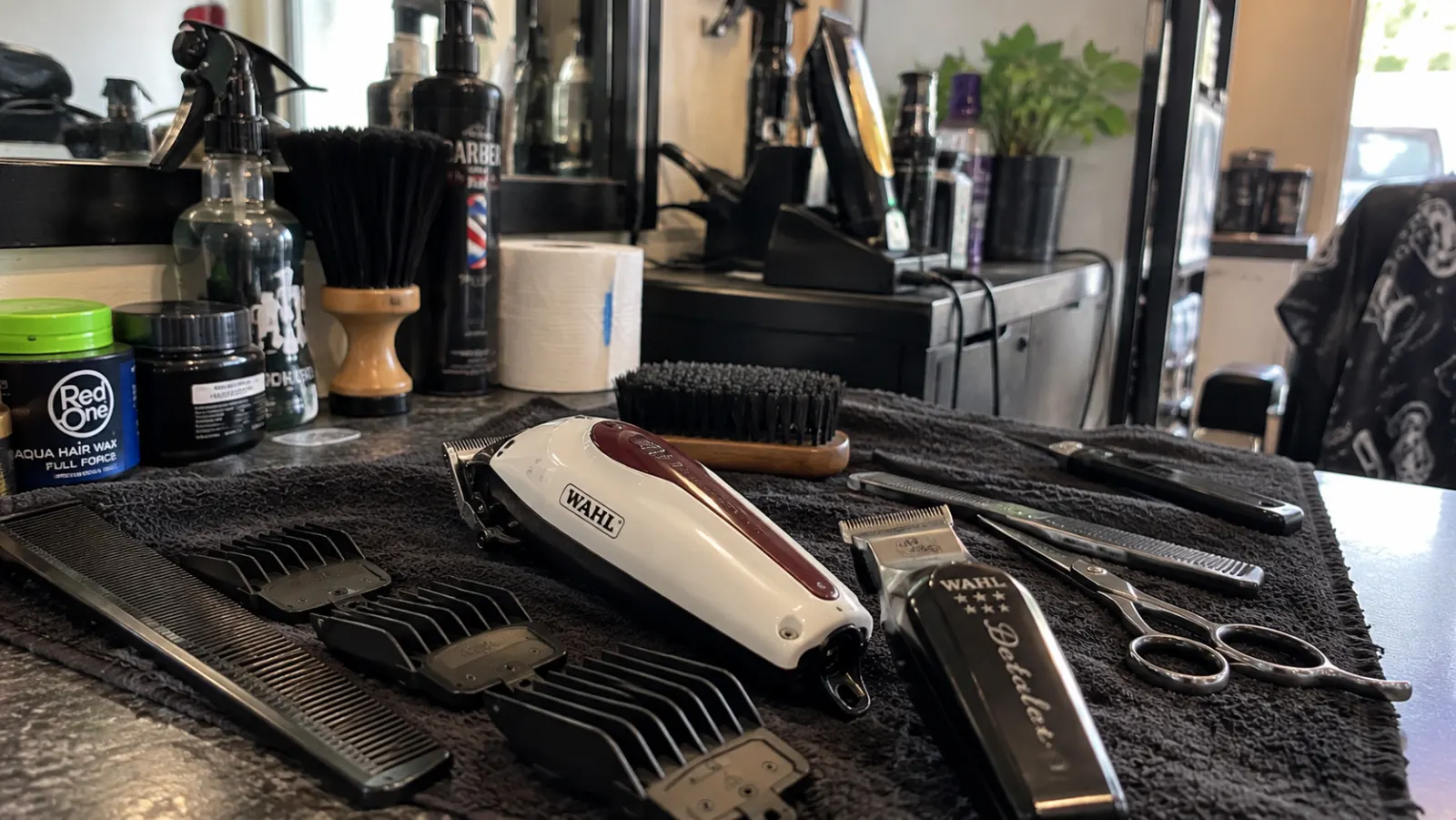 Clippers, guards, combs and scissors laid out on a barber's towel
